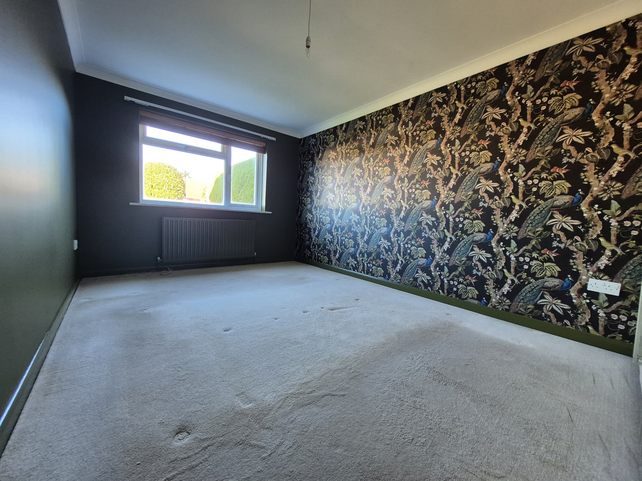 Bedroom with a dark botanical feature wallpaper wall, decorated by Paul Thomas