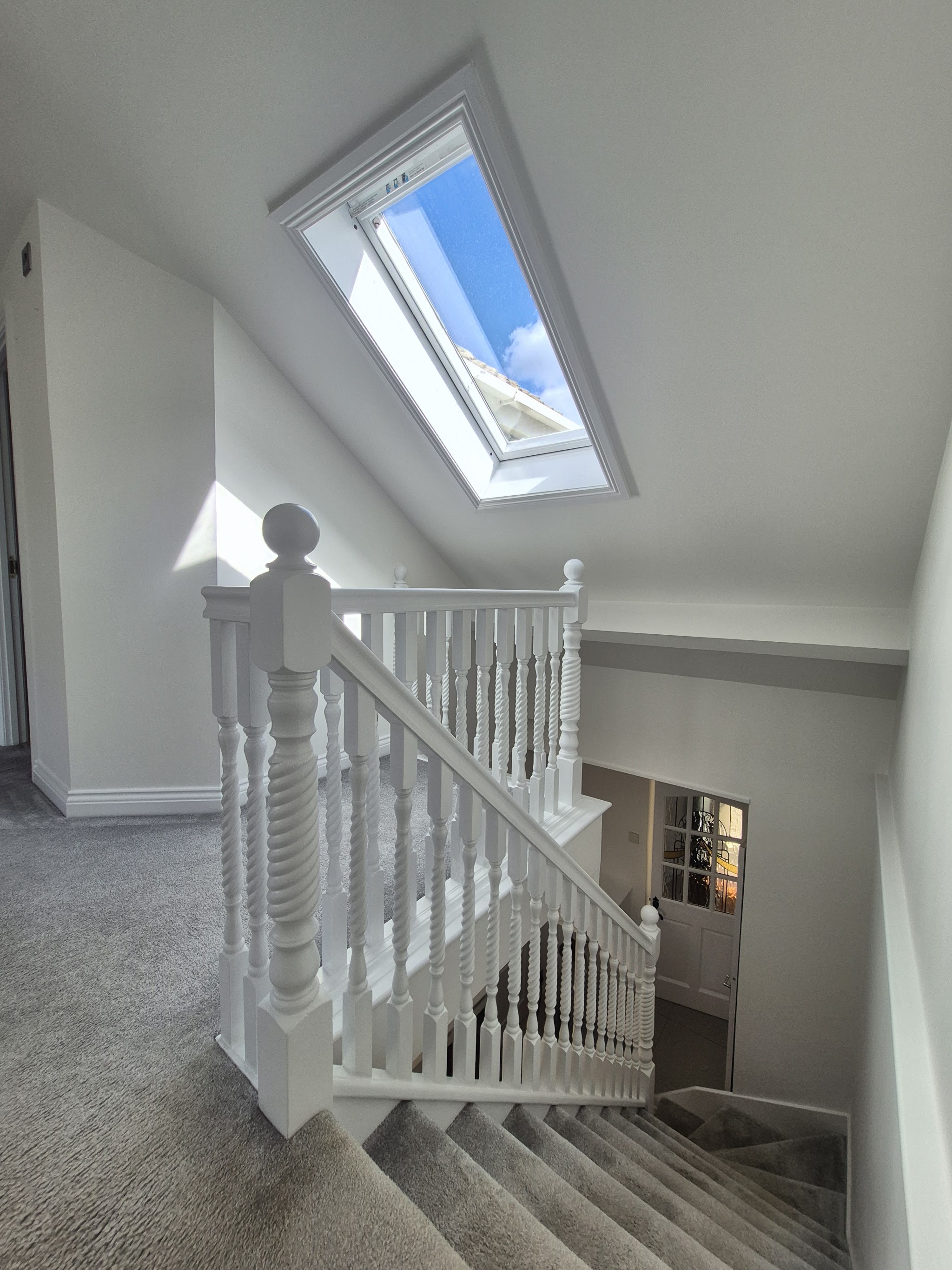 Landing and staircase with white turned balusters under a skylight