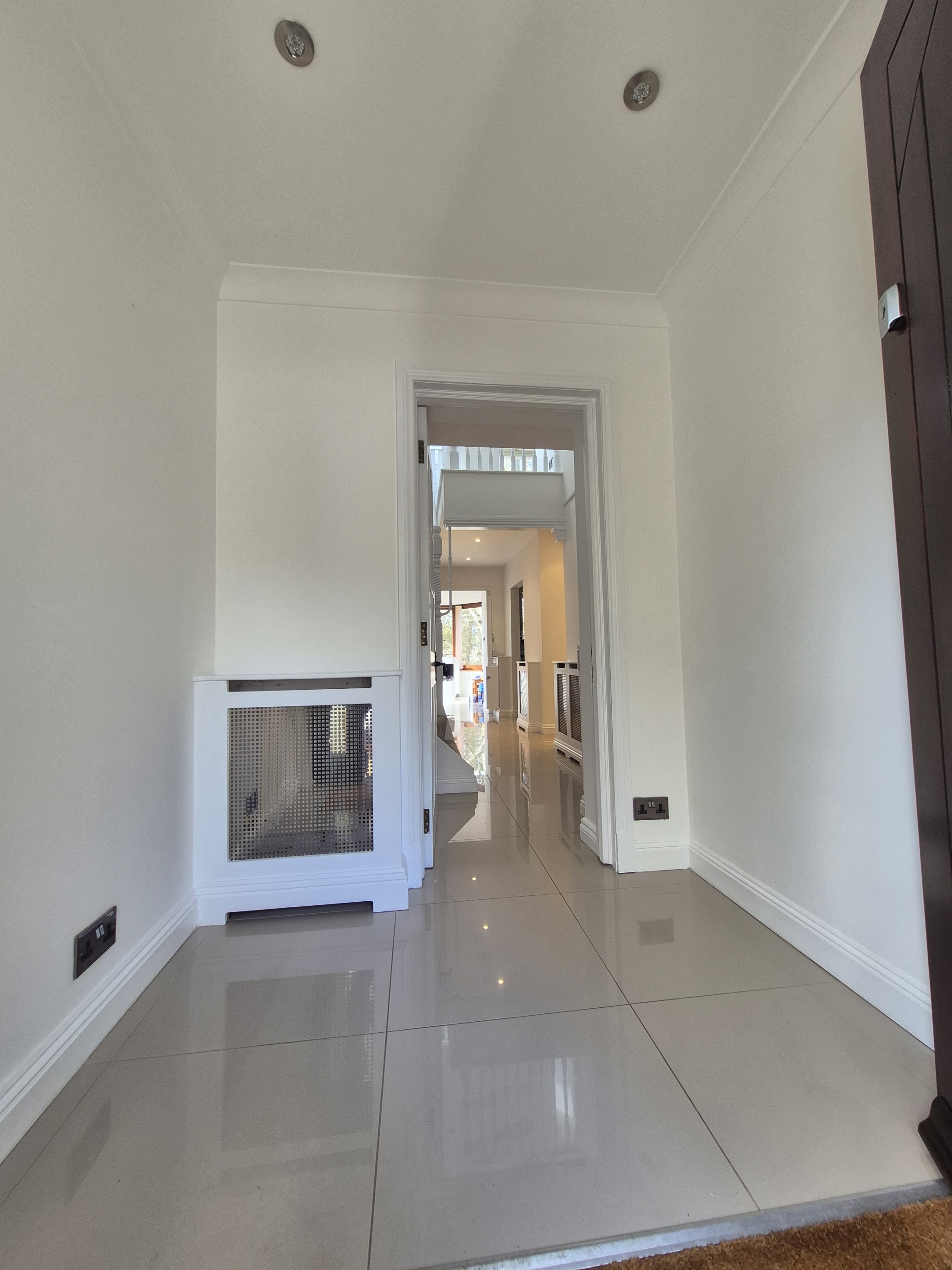 Bright white hallway with coving and a radiator cover